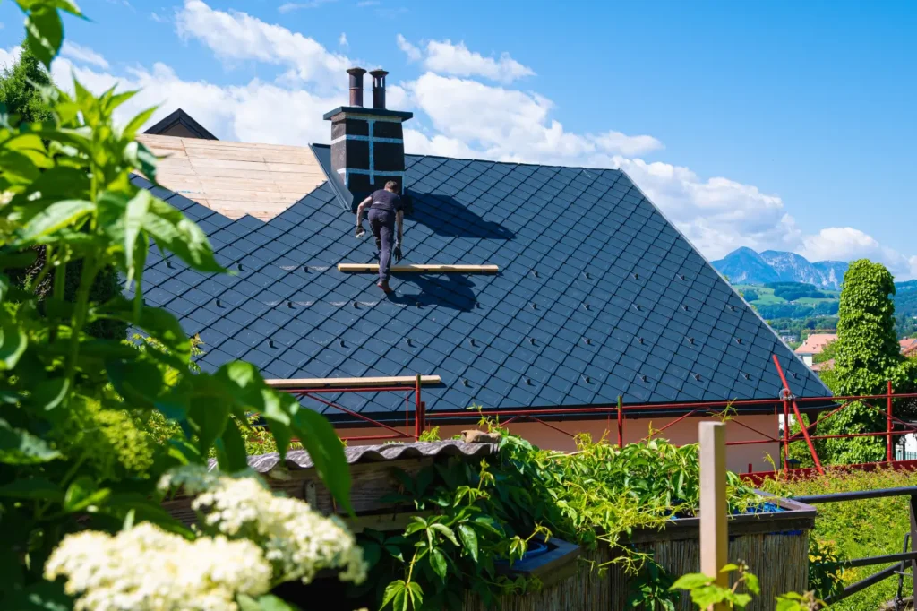 Dachdecker bei der Arbeit auf einem frisch eingedeckten Dach mit Bergpanorama im Hintergrund